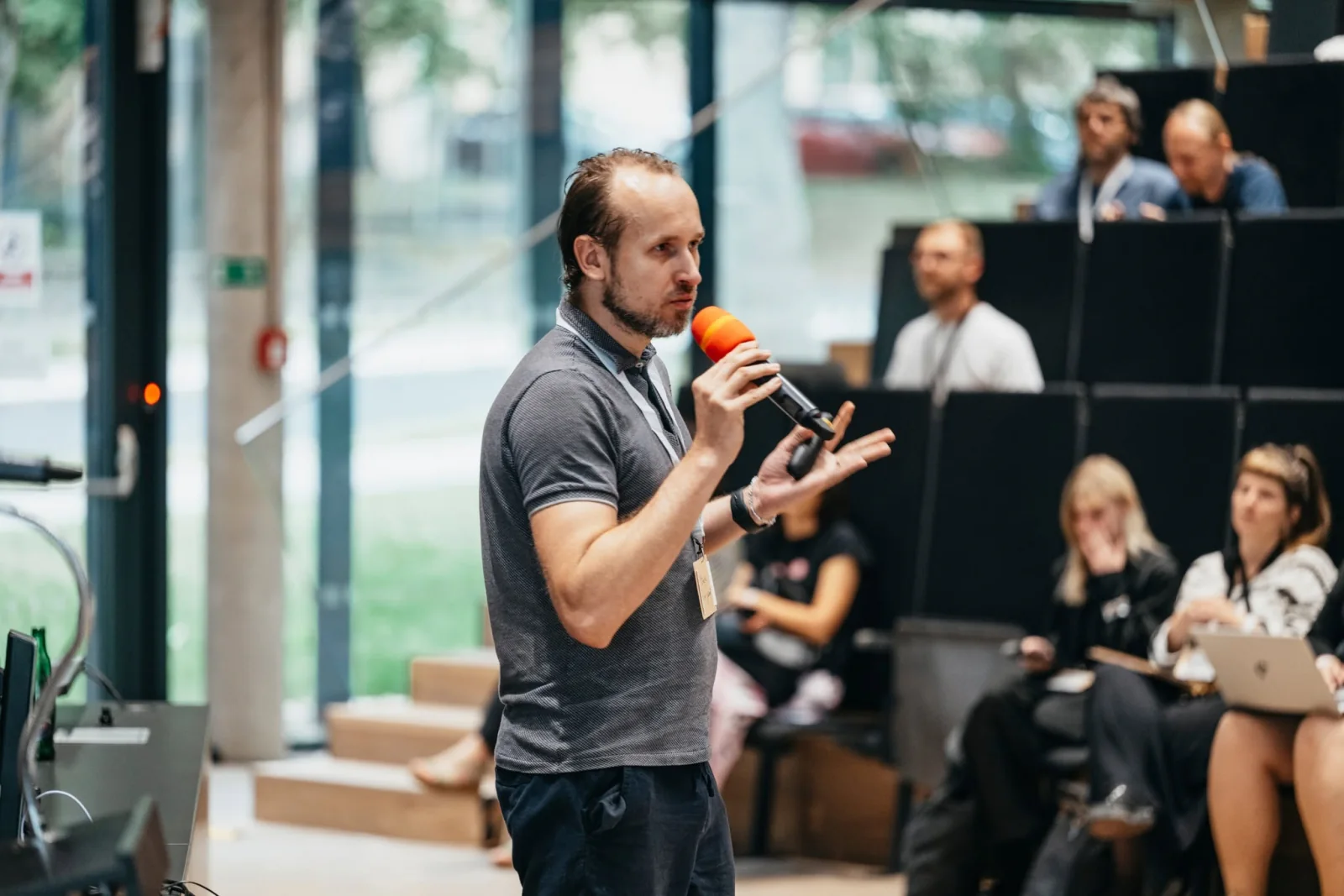 Jakub Roh s mikrofonem při vystoupení na konferenci před publikem